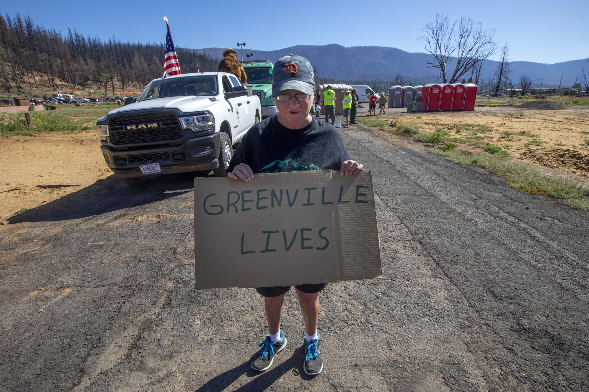 Cathy Buchanan holds a handmade cardboard "Greenville Lives" sign at the start of the Gold Diggers Day parade in Greenville.