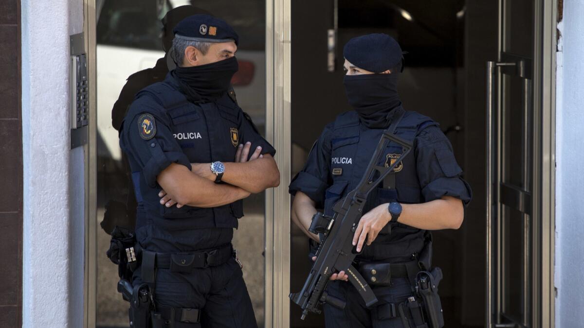 Catalan police officers stand guard at the entrance of a building during a raid following an attack near Barcelona, Spain, on Aug. 20.