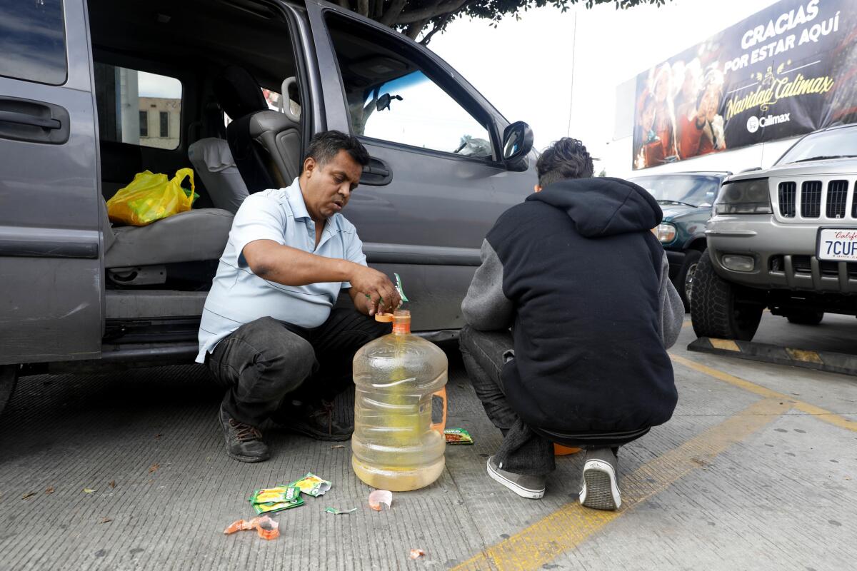 Irineo Mujica, a leader with Pueblo Sin Fronteras, shown with volunteer Cesar Yanez, 17, of Honduras, prepares drinks for members of the migrant caravan in Tijuana on Nov. 28, 2018.