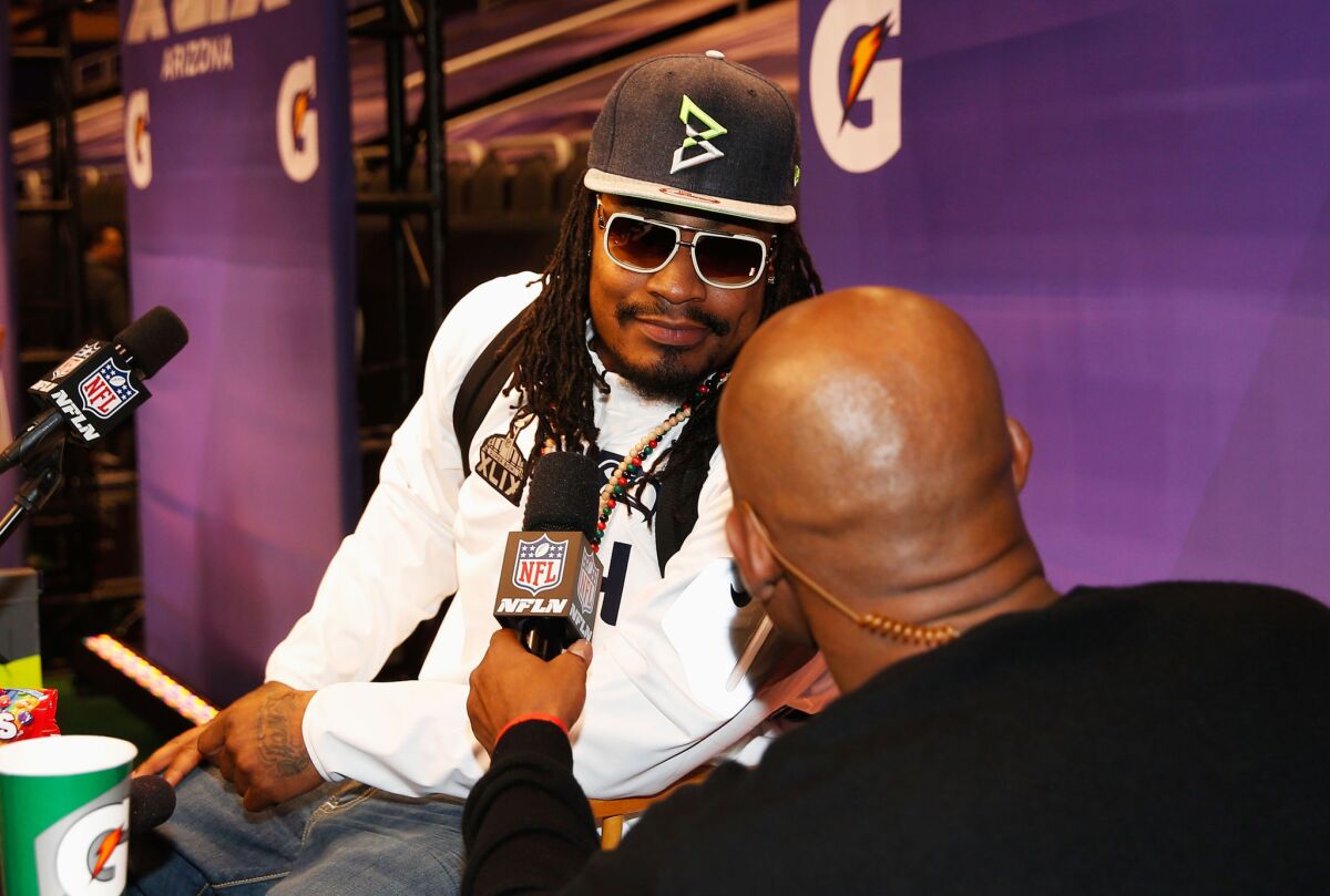 Seattle running back Marshawn Lynch talks with NFL Network's Deion Sanders during Super Bowl XLIX media day Tuesday in Phoenix.