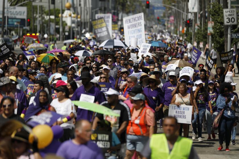 LOS ANGELES, CALIF. -- MONDAY, SEPTEMBER 2, 2019: Kaiser Permanente workers along with patients, clergy, elected leaders and community allies hold a protest against the healthcare giant’s unfair labor practices and shift from prioritizing patients and the community to profits and enriching top executives in Los Angeles, Calif., on Sept. 2, 2019. Protestors marched one mile to the Kaiser Permanente Medical Center, 4867 Sunset Blvd. in Hollywood, where dozens of them were arrested for civil disobedience by blocking an intersection near the facility. (Gary Coronado / Los Angeles Times)