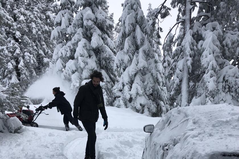 Visiting family members of residents help dig an access road out of the snow on Friday in Twin Peaks, an area two miles west of Lake Arrowhead.