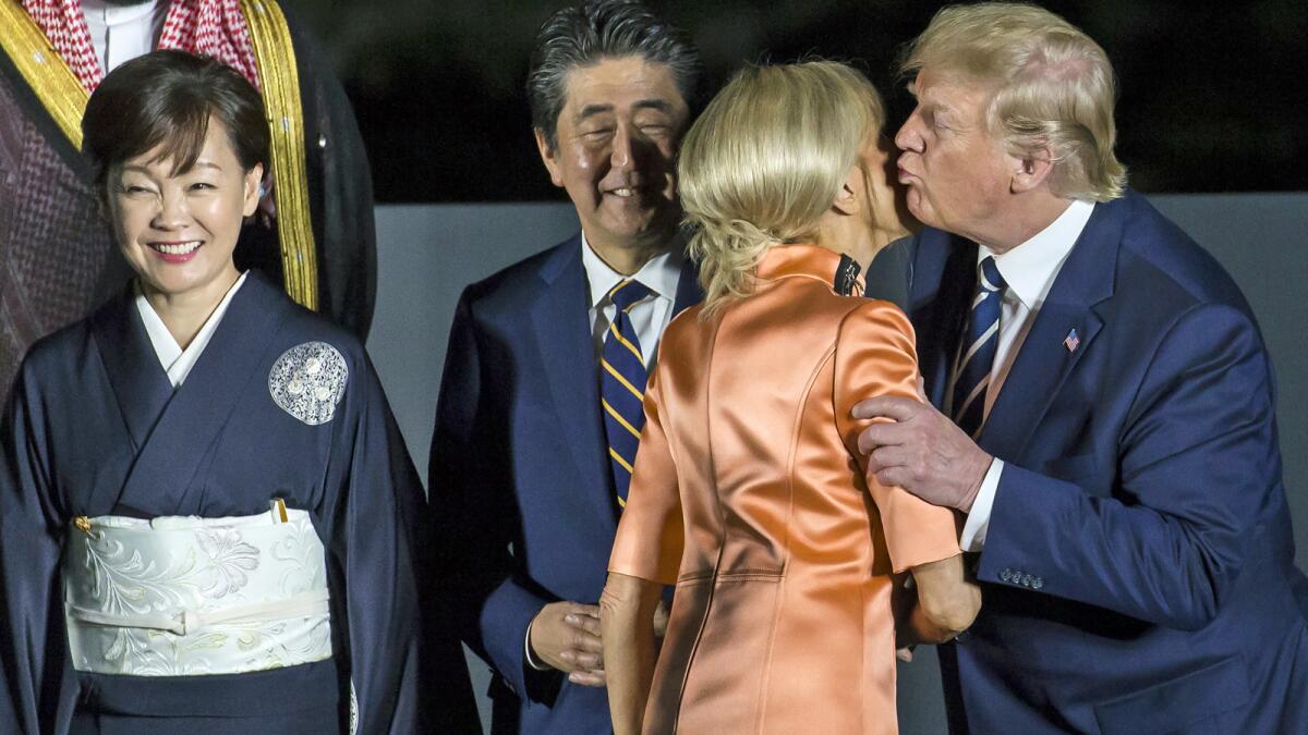 President Trump kisses Brigitte Macron, wife of the French president, as Japanese Prime Minister Shinzo Abe and his wife Akie Abe look on Friday.