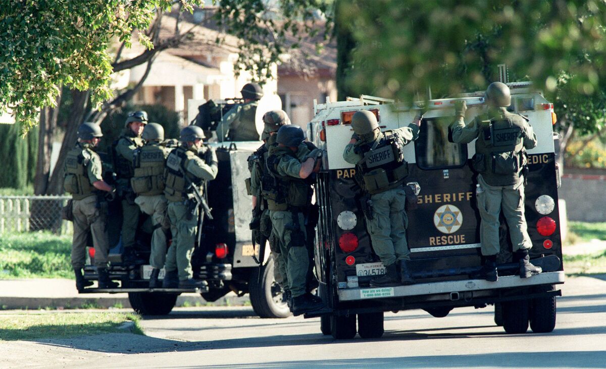 Armored personnel carriers move down Radford Street in a house–by–house search for a suspect. (Damian Dovarganes / Associated Press)