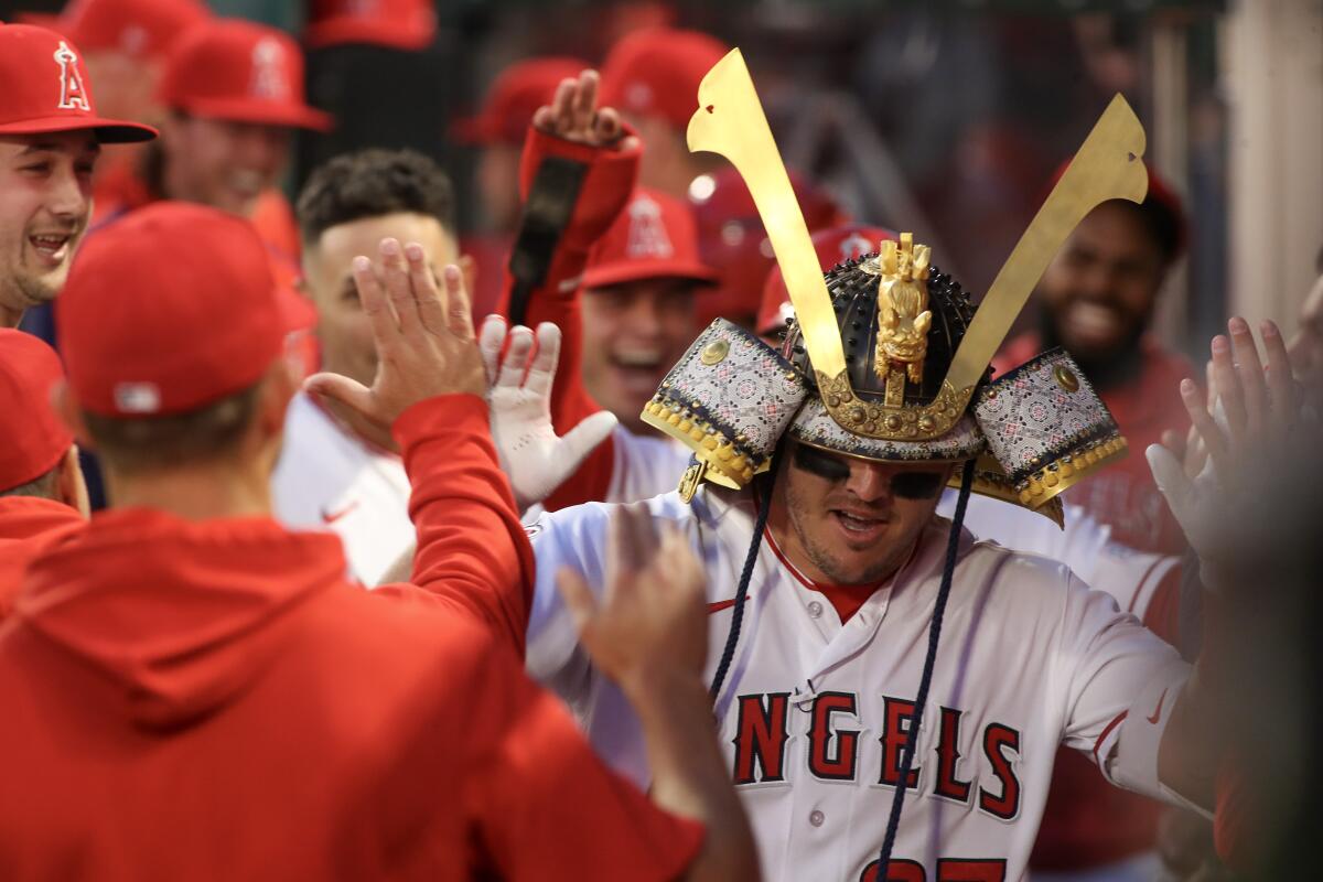 Mike Trout gets high fives in the dugout after blasting a two-run homer in the first inning of the Angels' 4-3 loss.