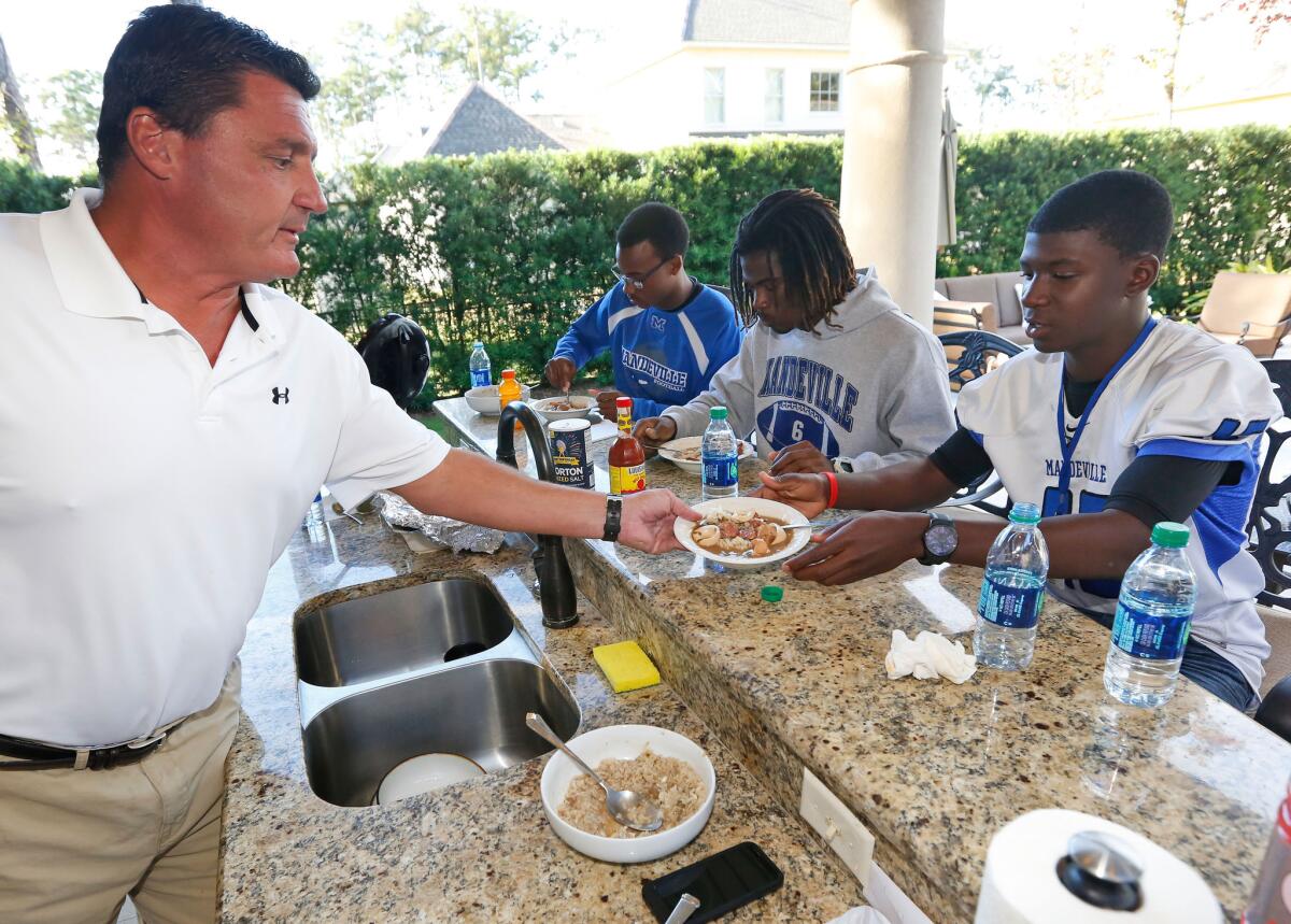 Former USC coach Ed Orgeron serves a bowl of gumbo to Mandeville High football player Darren Steele at his home this fall.