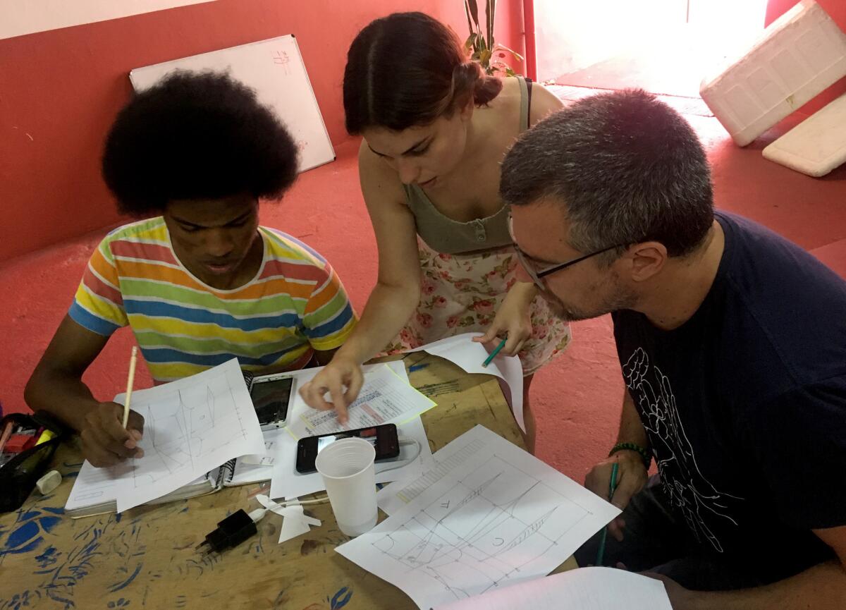 Nawira Scarano, center, teaches Reinaldo da Silva Freitas Jr., left, and another student how to use measurements to make a pattern in her sewing class at the Casa 1 community center in São Paulo, Brazil.