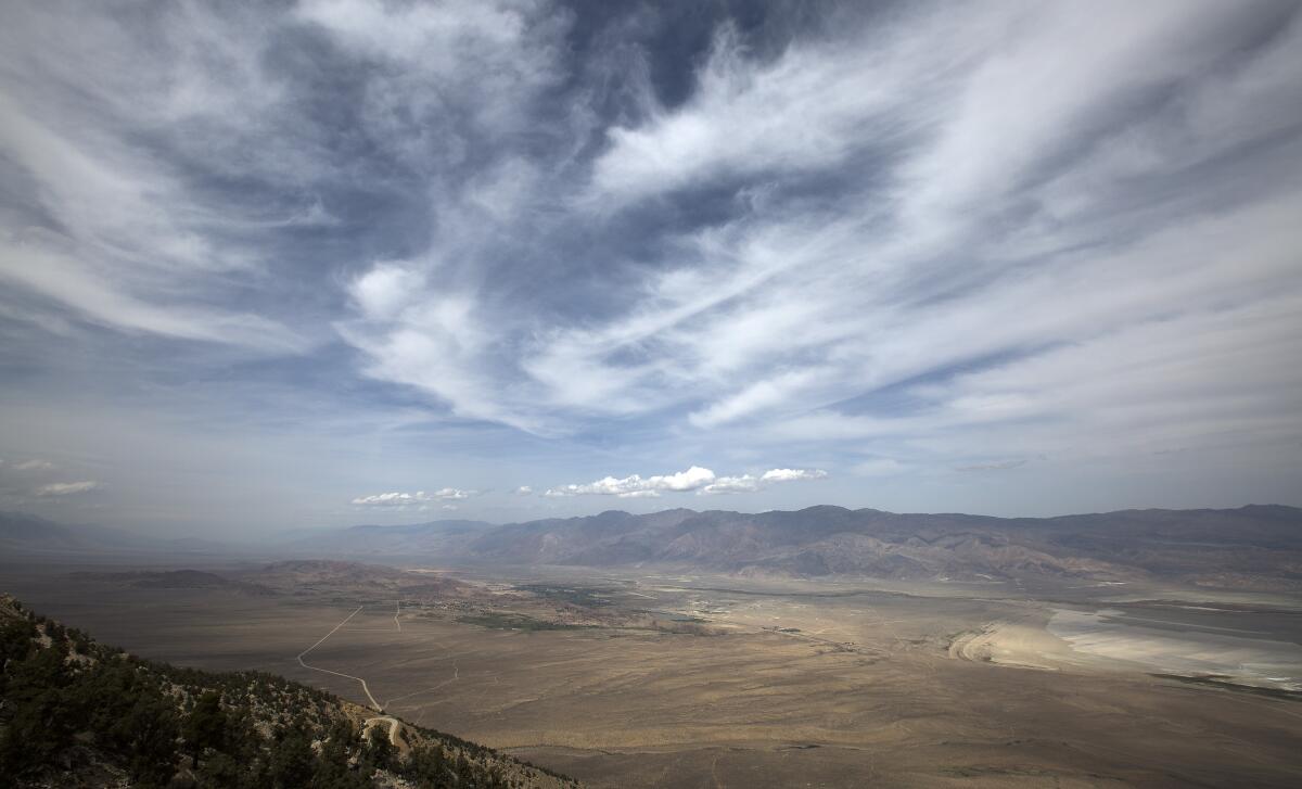 Aerial view of a large valley, with wispy clouds above.