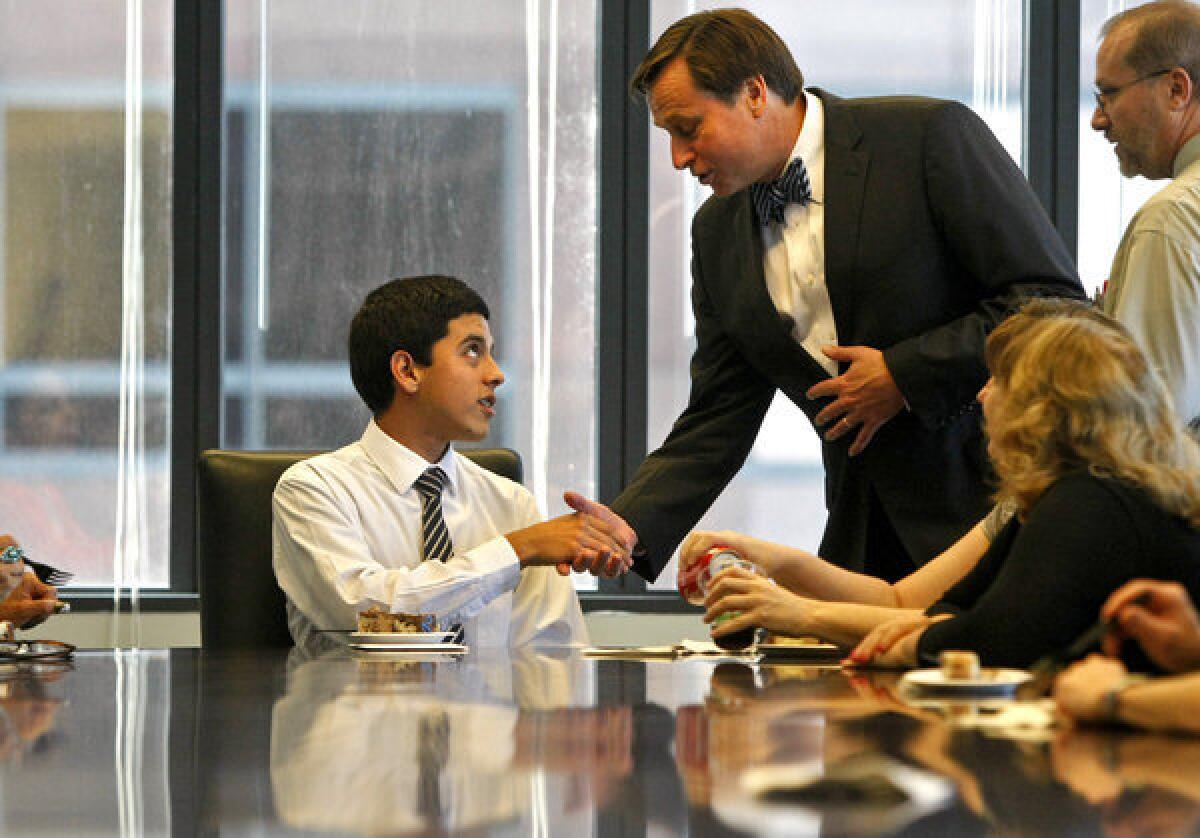 During a party commemorating his years of internship at Locke Lord in downtown L.A., Ricardo Placensia shakes hands with Jon Rewinski, a partner in the law firm. For many years the Jesuit-run Verbum Dei High School has achieved the remarkable distinction of sending 100% of its graduates to a college or university.