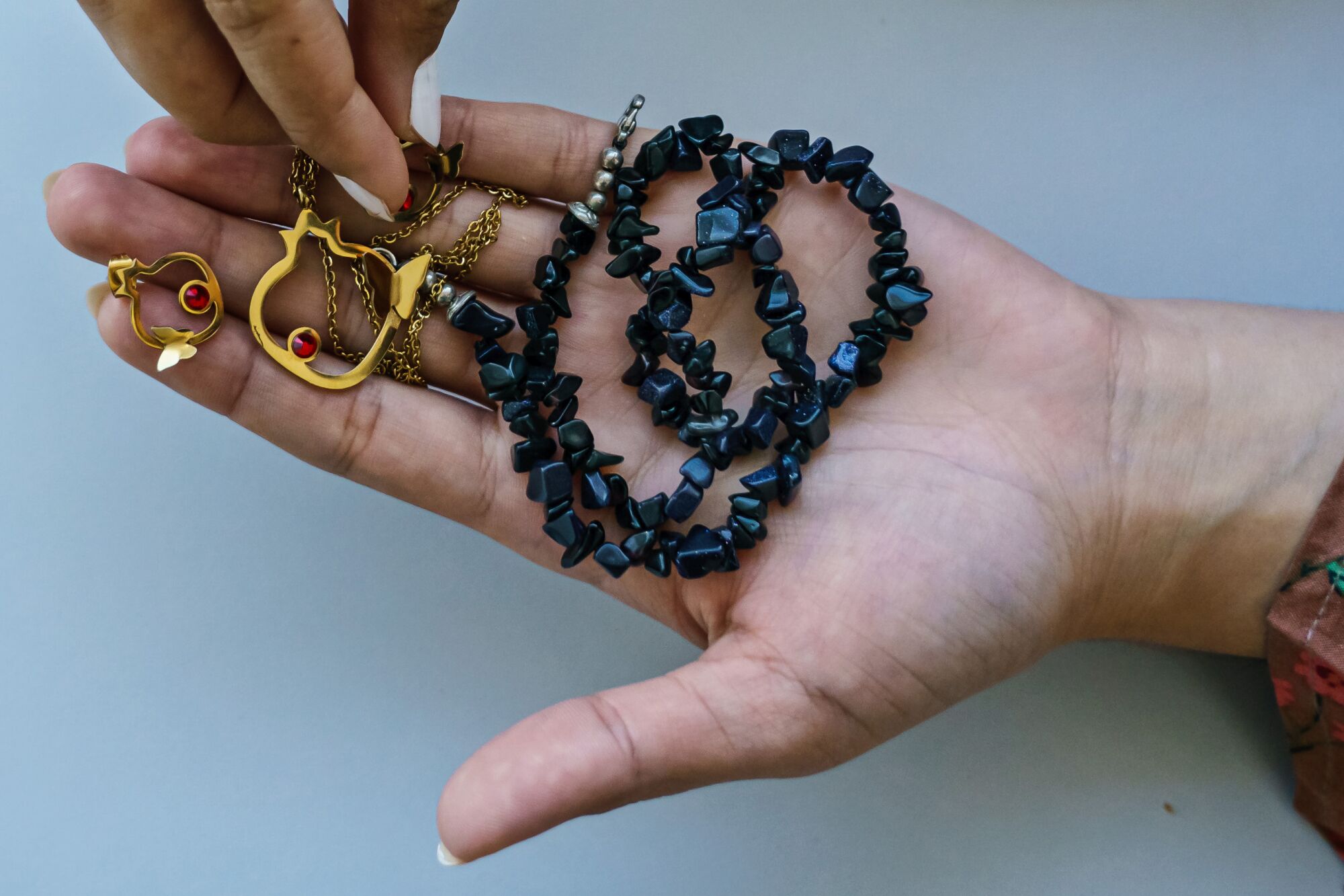 A black stone necklace held in a hand