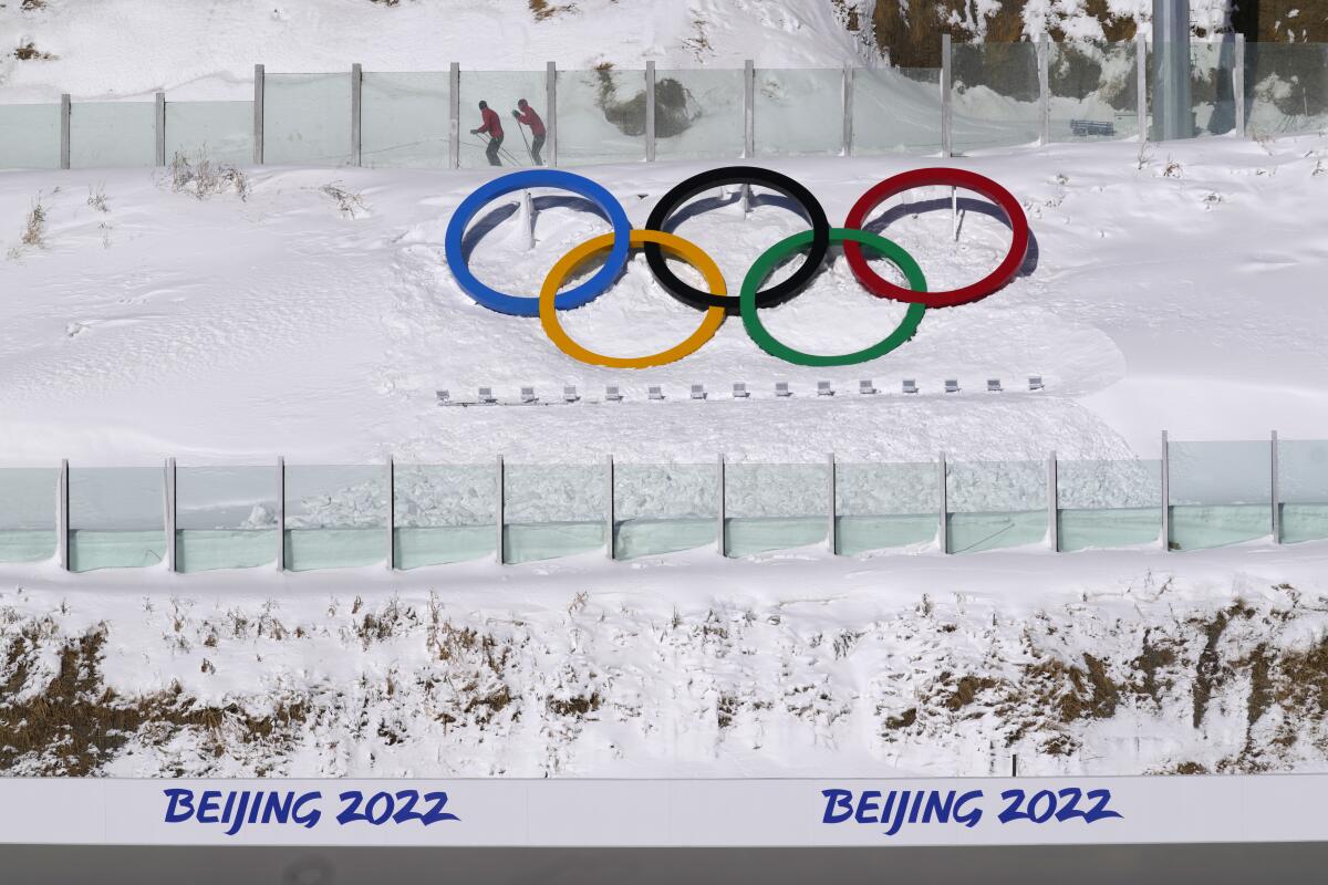 Biathletes compete above the Olympic rings
