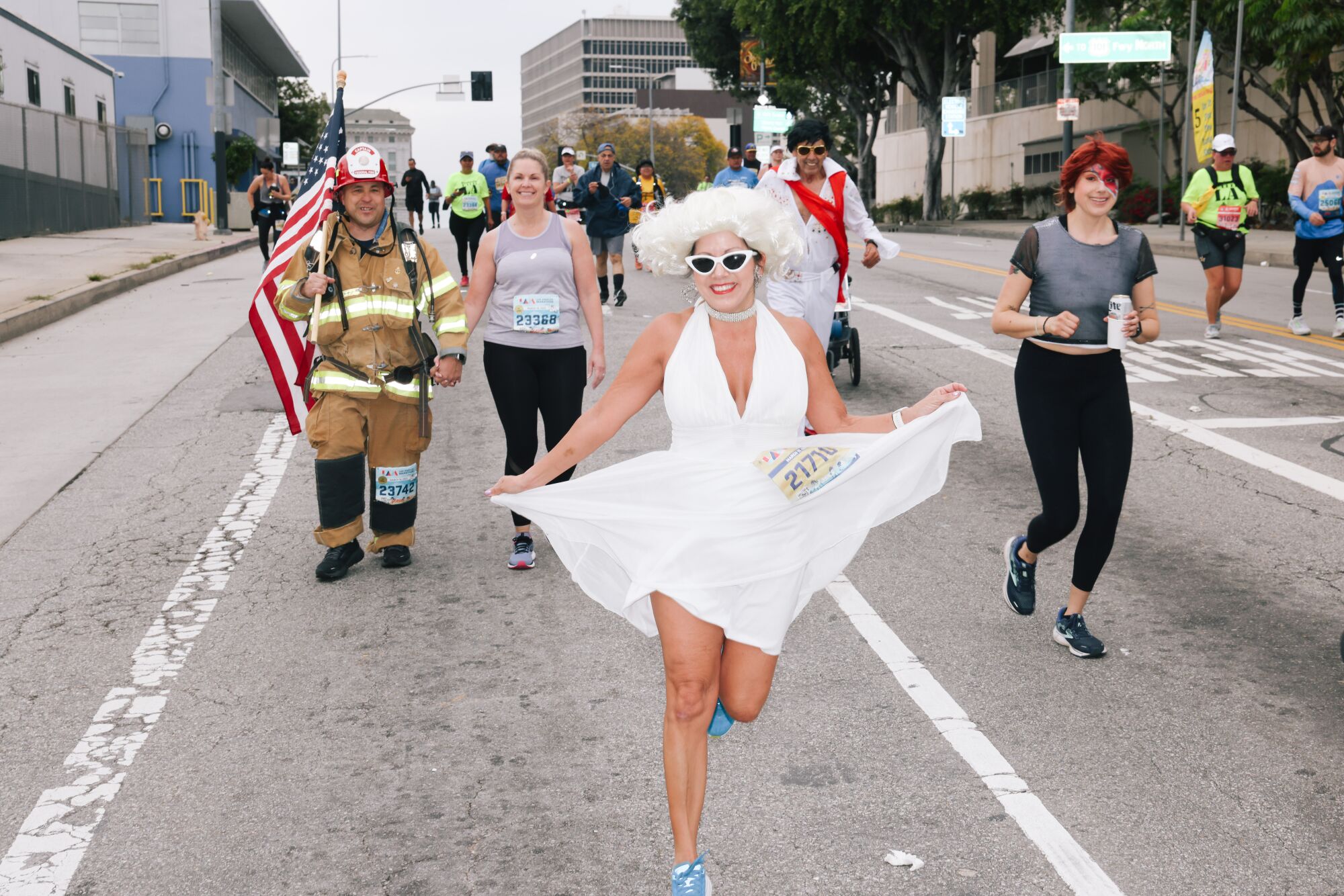 A runner dressed as Marilyn Monroe in a wig, sunglasses and white dress on the track.