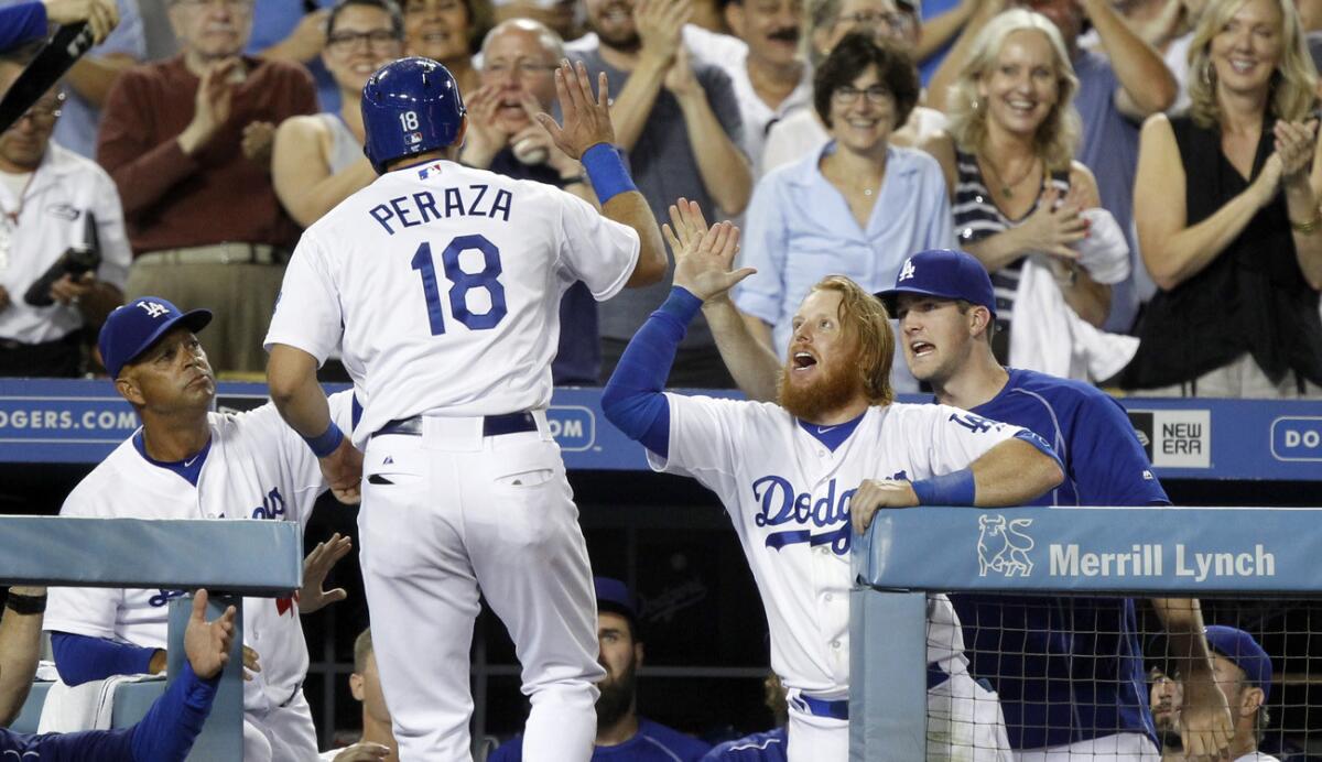 Dodgers second baseman Jose Peraza is congratulated by third baseman Justin Turner after scoring on a hit by Andre Ethier in the seventh inning against the Cubs on Saturday night.