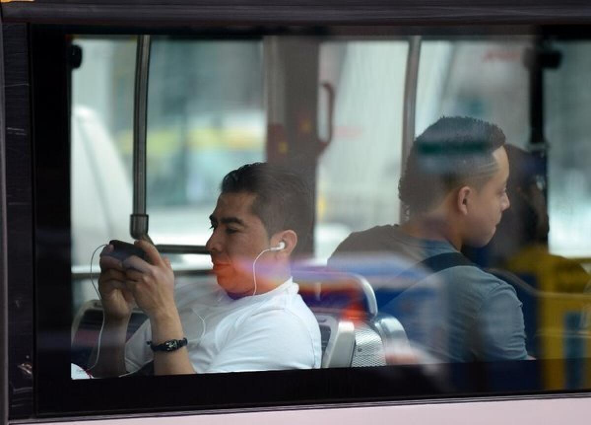 A man uses his smartphone while riding a bus in Washington, D.C. in May 2012