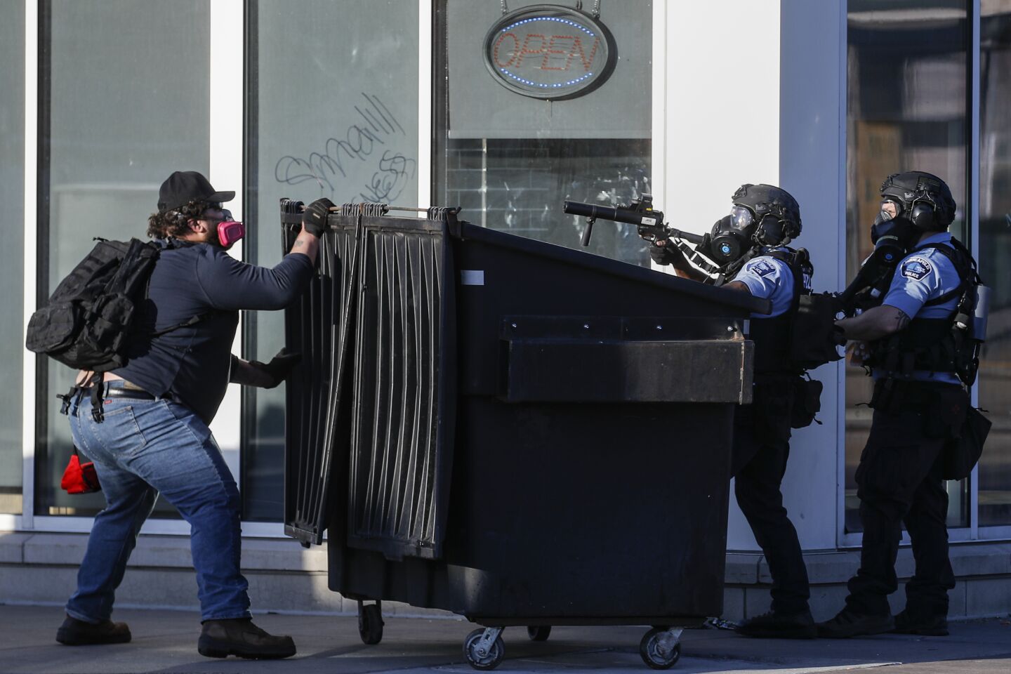 A protester faces off with two police officers using less-lethal ammunition in their weapons in St. Paul.