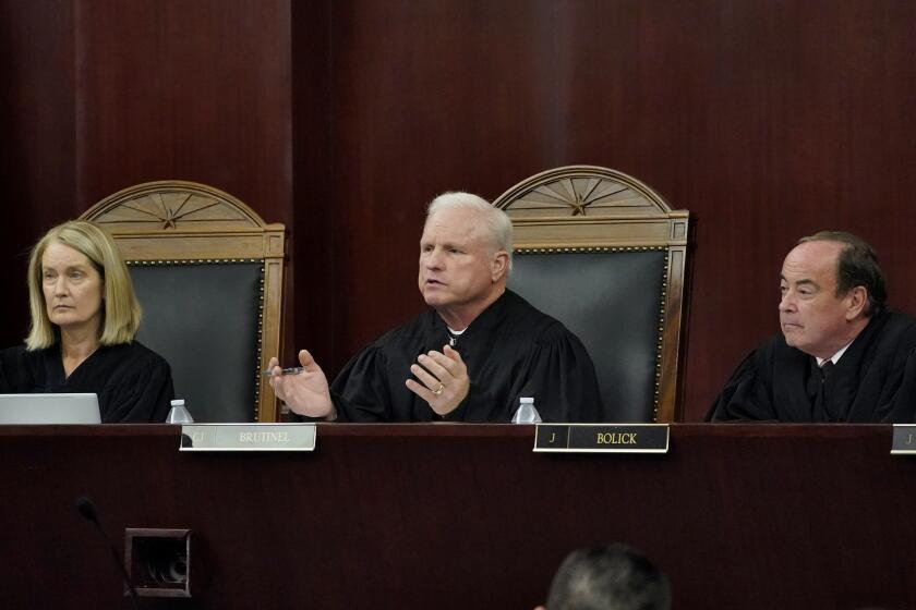 Arizona Supreme Court Chief Justice Robert M. Brutinel, center, speaks during oral arguments, Tuesday, April 20, 2021, in Phoenix as Vice Chief Justice Ann A. Scott Timmer, left, and Justice Clint Bolick listen. The Arizona Supreme Court heard an expedited constitutional challenge to a new voter-approved tax on high-earning Arizonans designed to boost school funding on Tuesday. (AP Photo/Matt York)
