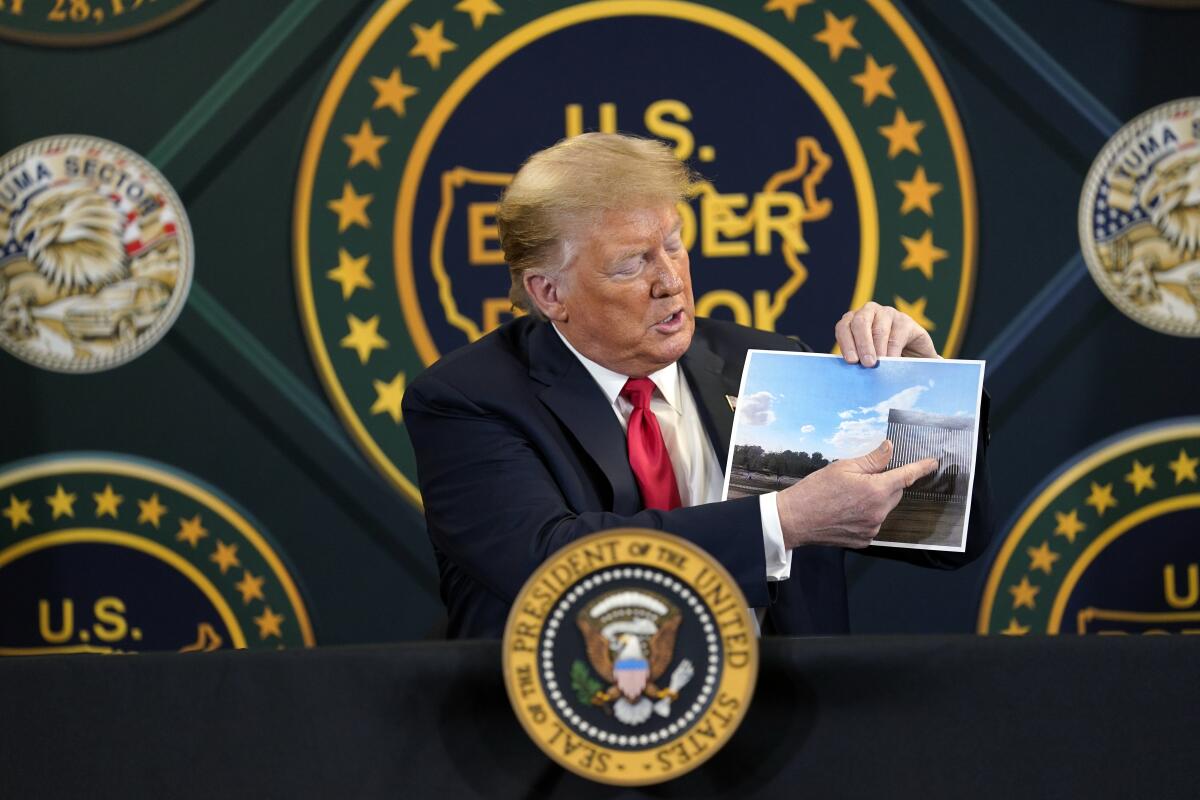 El presidente Trump muestra una foto de secciones recientemente terminadas del muro fronterizo.