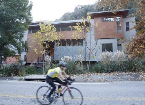 A bicyclist pedals past a large modern home in Mandeville Canyon, a rustic neighborhood in the Brentwood area of Los Angeles.