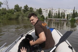 Un equipo de rescate animal se desplaza el jueves 8 de junio de 2023 en una embarcación con un perro al que han salvado en una zona inundada tras la ruptura de una represa en Jersón, Ucrania. (AP Foto/Vasilisa Stepanenko)
