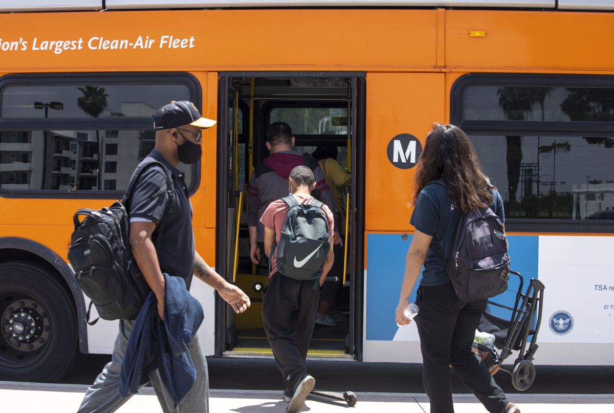 Passengers board an orange L.A. Metro bus
