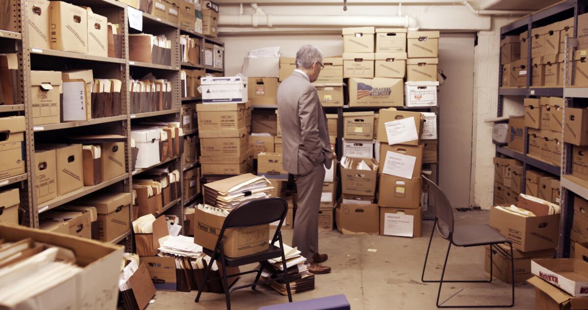 A man in a suit looks at a room full of boxes