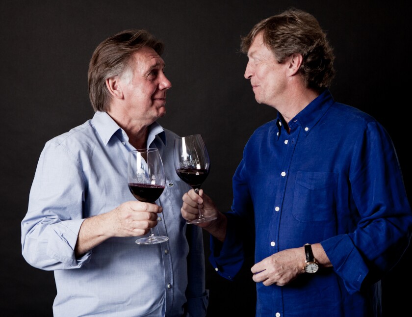 Ken Warwick (left) and Nigel Lythgow stand, each holding a wine glass and looking at each other