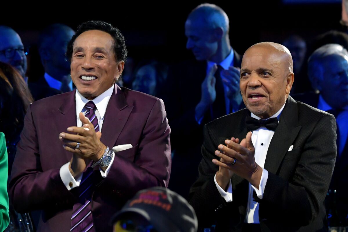 Smokey Robinson and Berry Gordy Jr. clap at an awards ceremony.