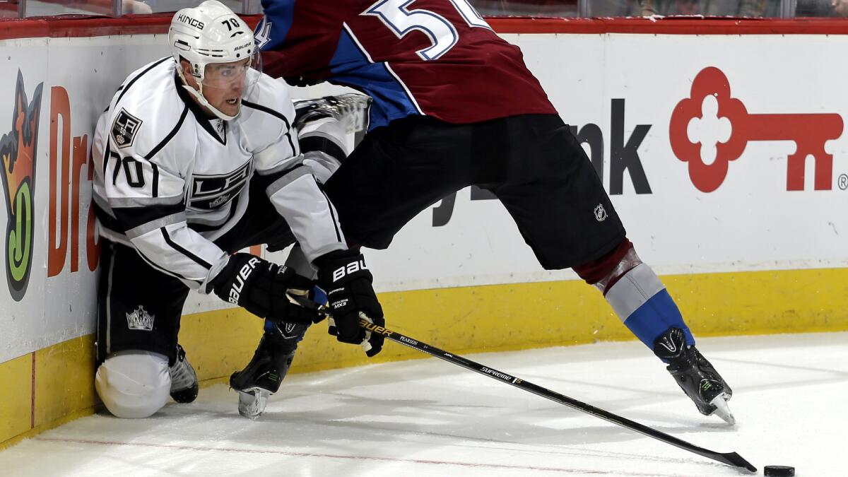 Kings forward Tanner Pearson tries to get the puck to a teammate after battling along the boards against Avalanche defenseman Anton Lindholm during the second period Friday.