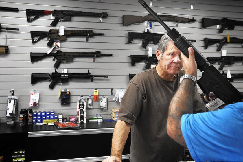 Frank Cobet of Get Loaded in Grand Terrace shows a customer a AR-15 rifle.