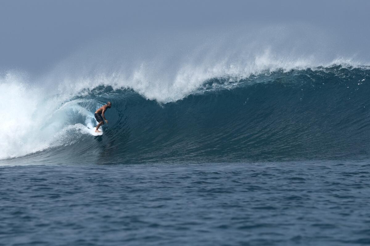 A surfer attempts to thread a tube section at Lance's Left, a reef break in Katiet, Indonesia