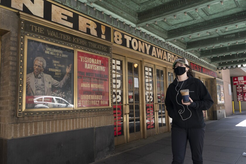 A woman walks past the Walter Kerr Theatre, Thursday, May 6, 2021, in New York where Hadestown was showing before the coronavirus pandemic forced its closing a year ago. Gov. Andrew Cuomo has announced that Broadway theaters can reopen Sept. 14, 2021. (AP Photo/Mark Lennihan)