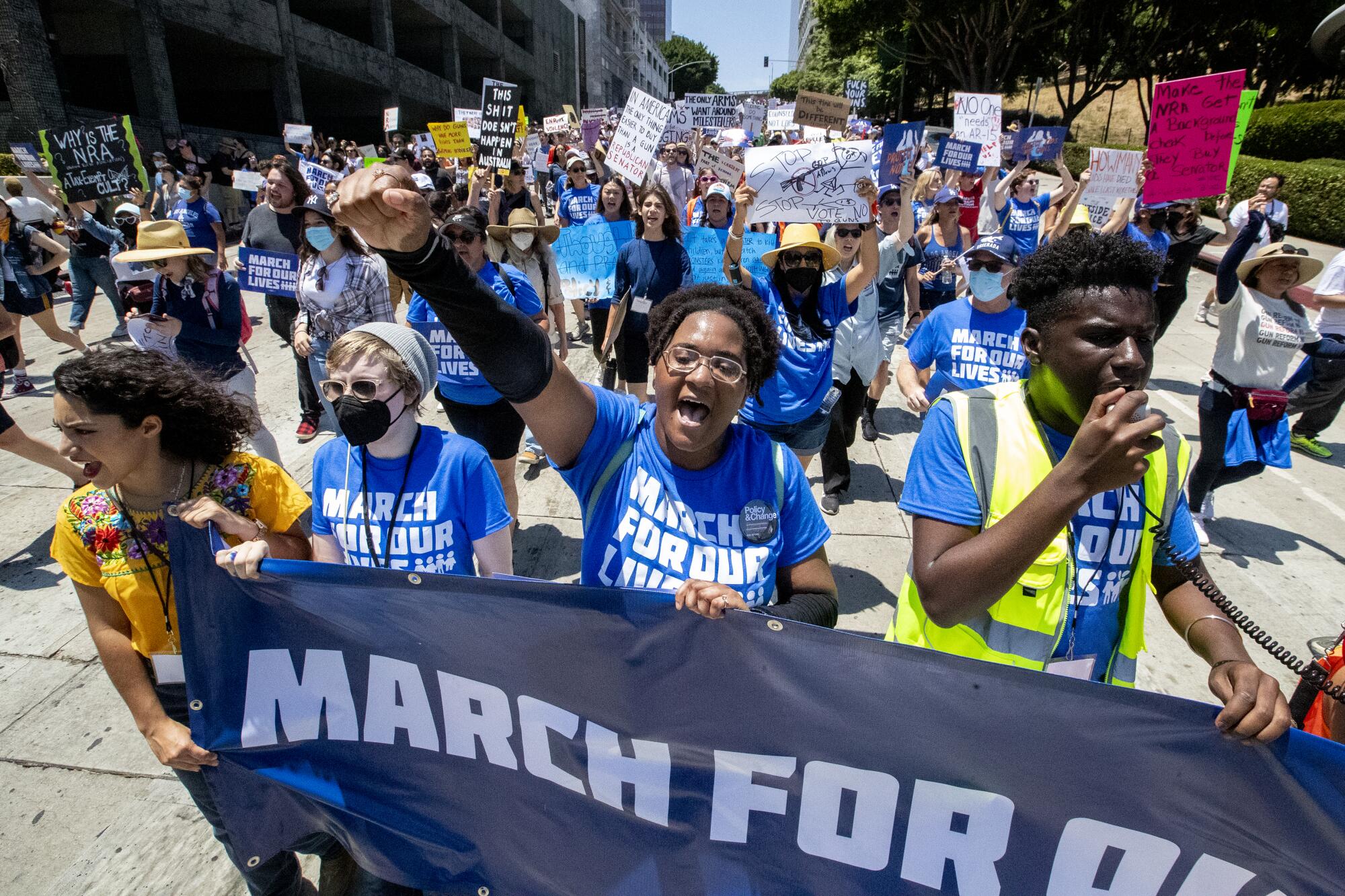 Marchers with signs and banners fill a wide city street.