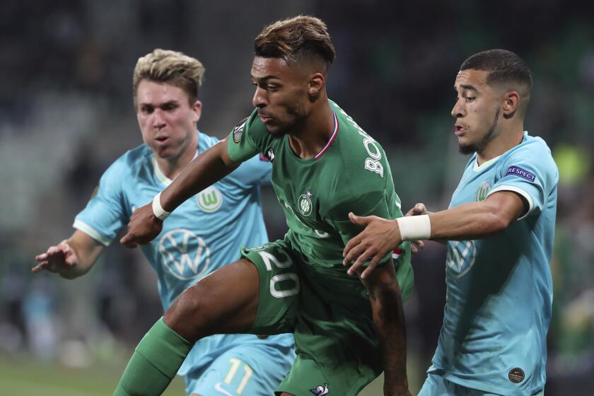 Saint-Etienne's Denis Bouanga, center, challenges for the ball with Wolfsburg's Felix Klaus, left, and William.