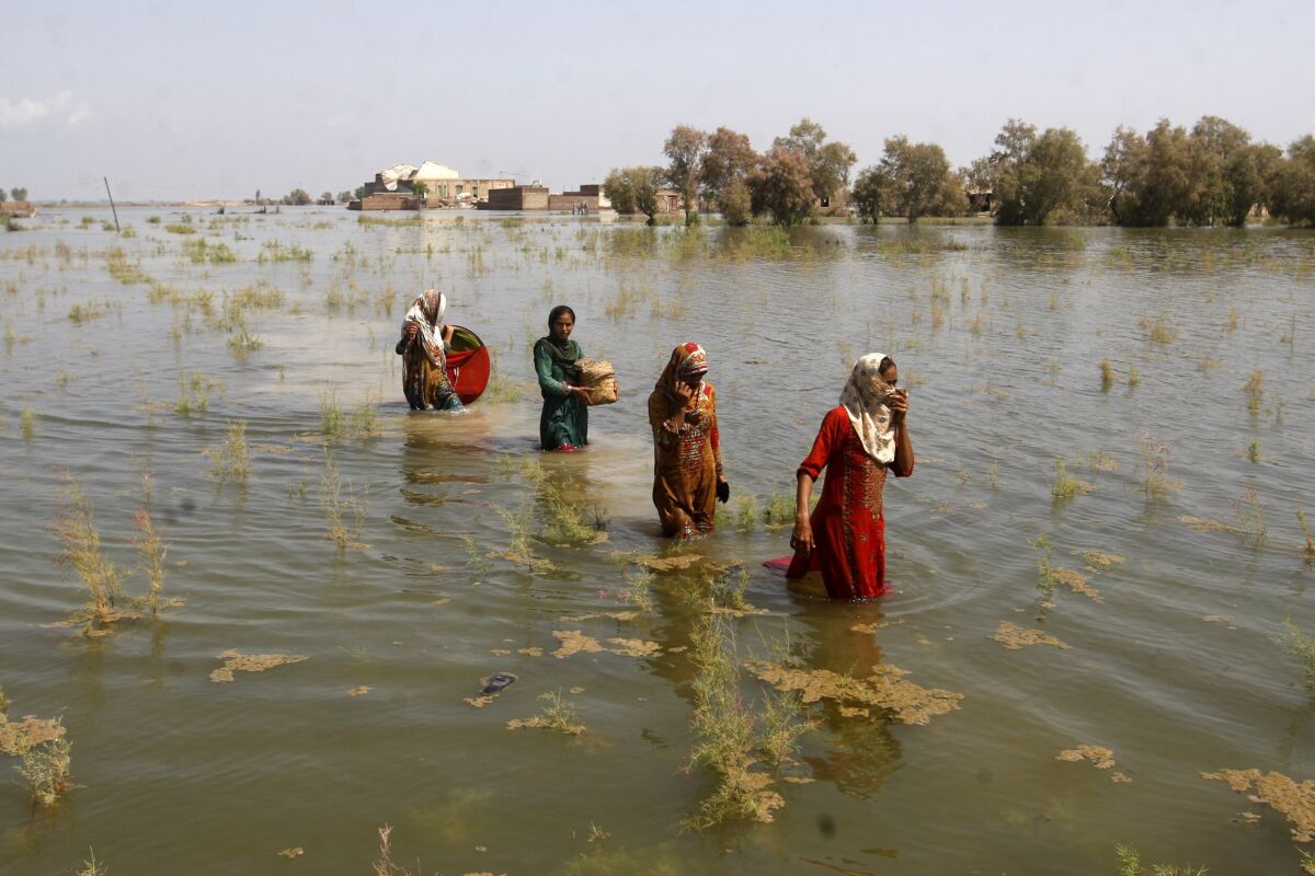 Women wade through floodwaters.