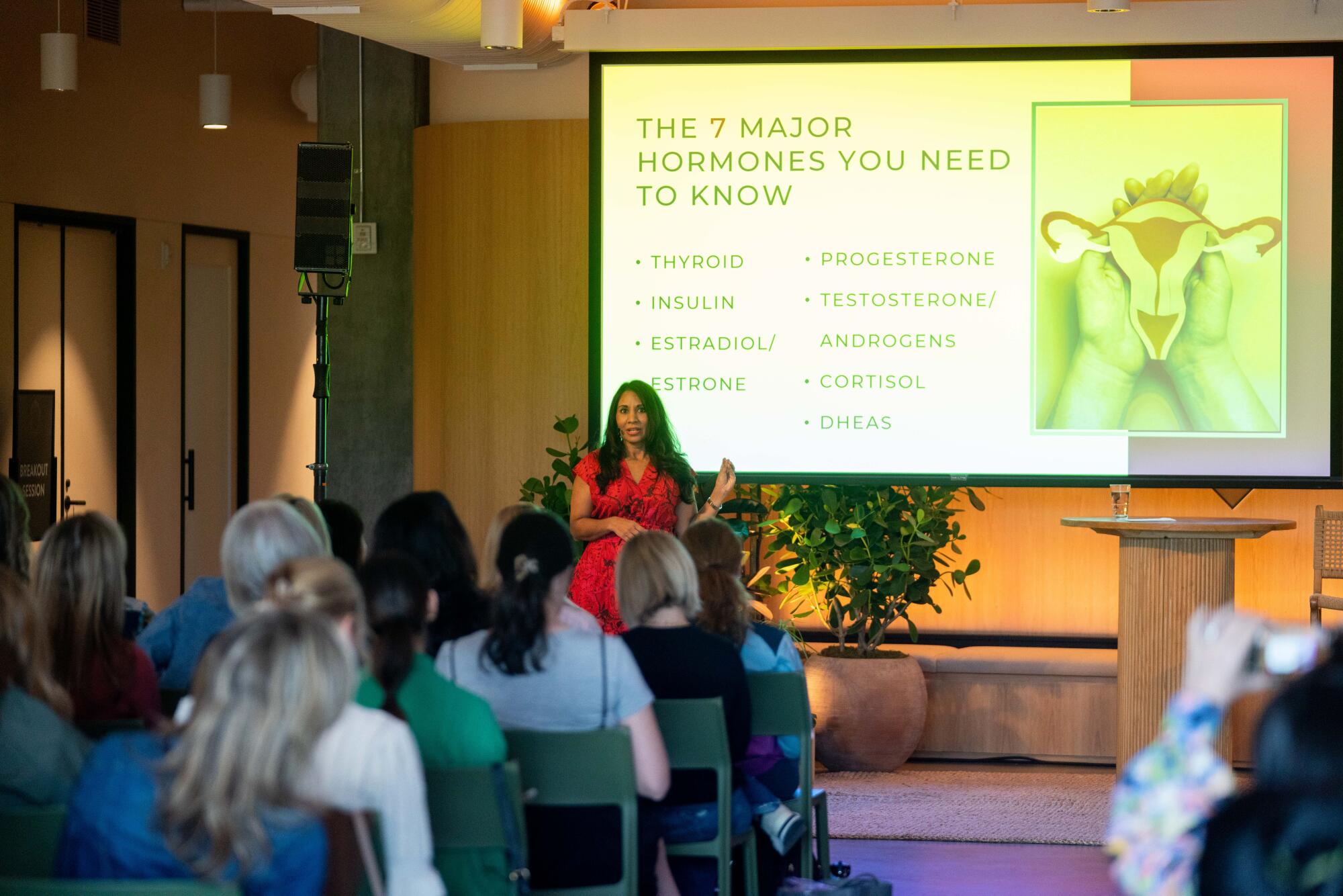 A speaker in front of a powerpoint presentation outlining types of hormones. 