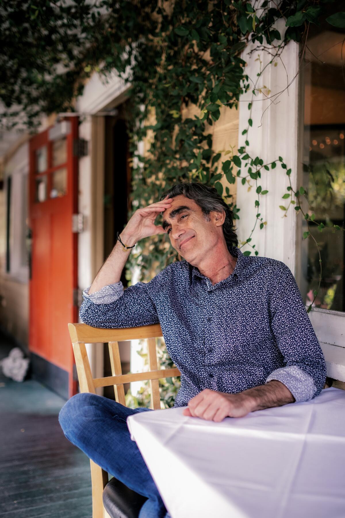 A man sits at a table on a porch.