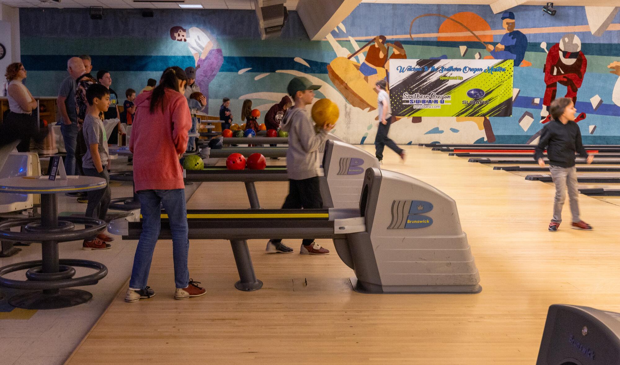 Kids bowl at a colorful bowling alley. 