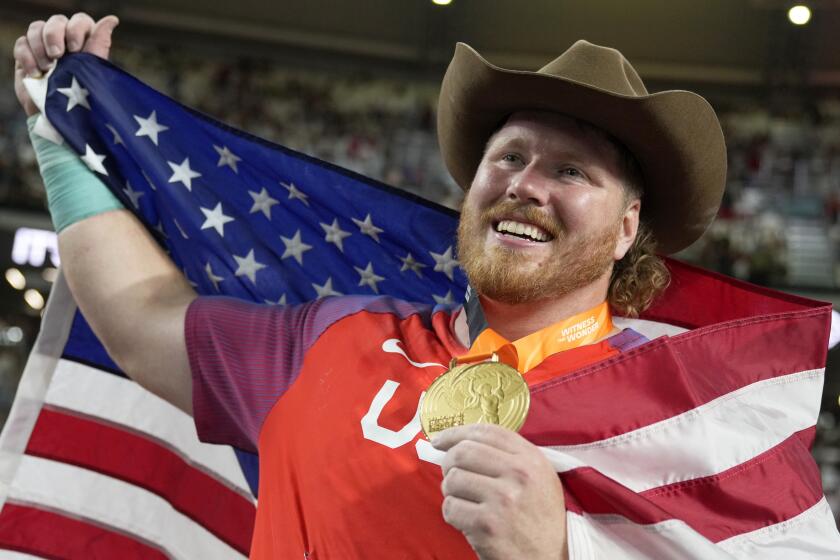 Ryan Crouser, of the United States, poses after winning the gold medal and setting a new.