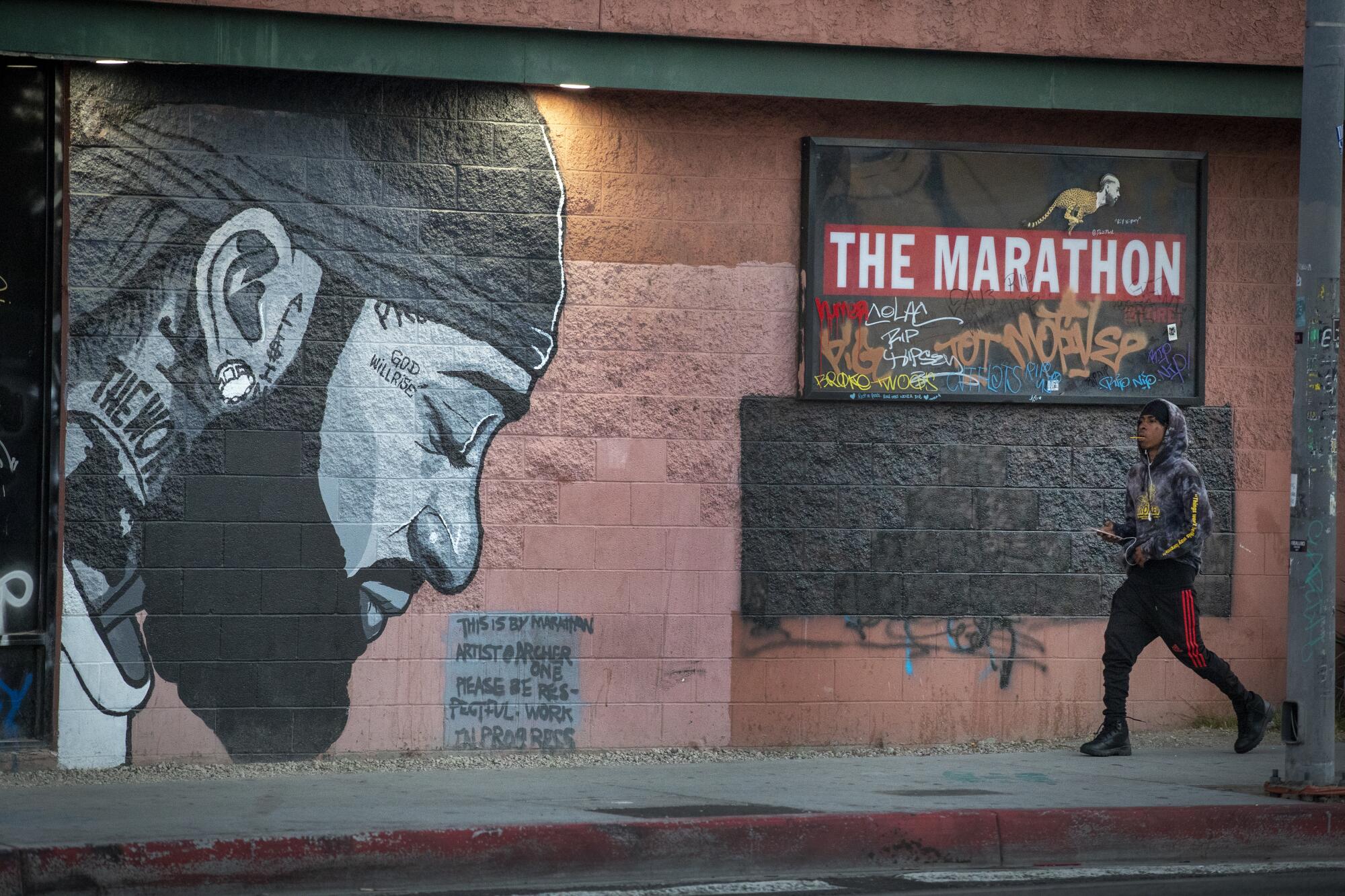 A Nipsey Hussle mural adorns the wall of a strip mall.