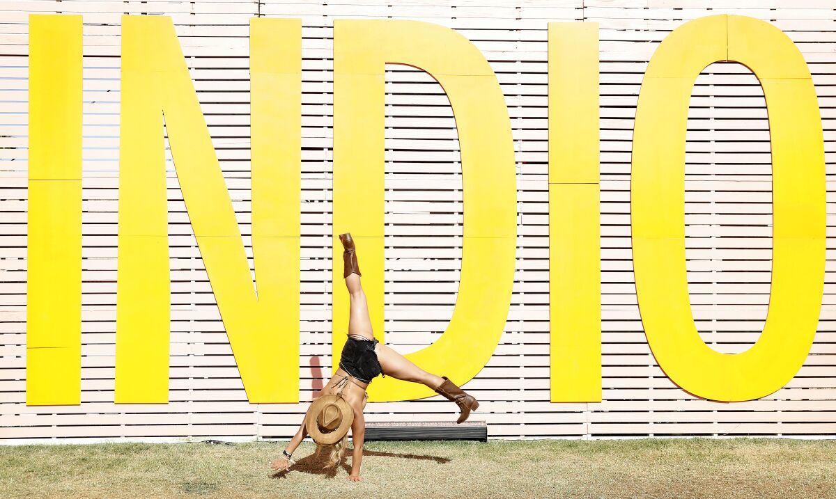 A woman does a cartwheel in front of a yellow sign that says "Indio"