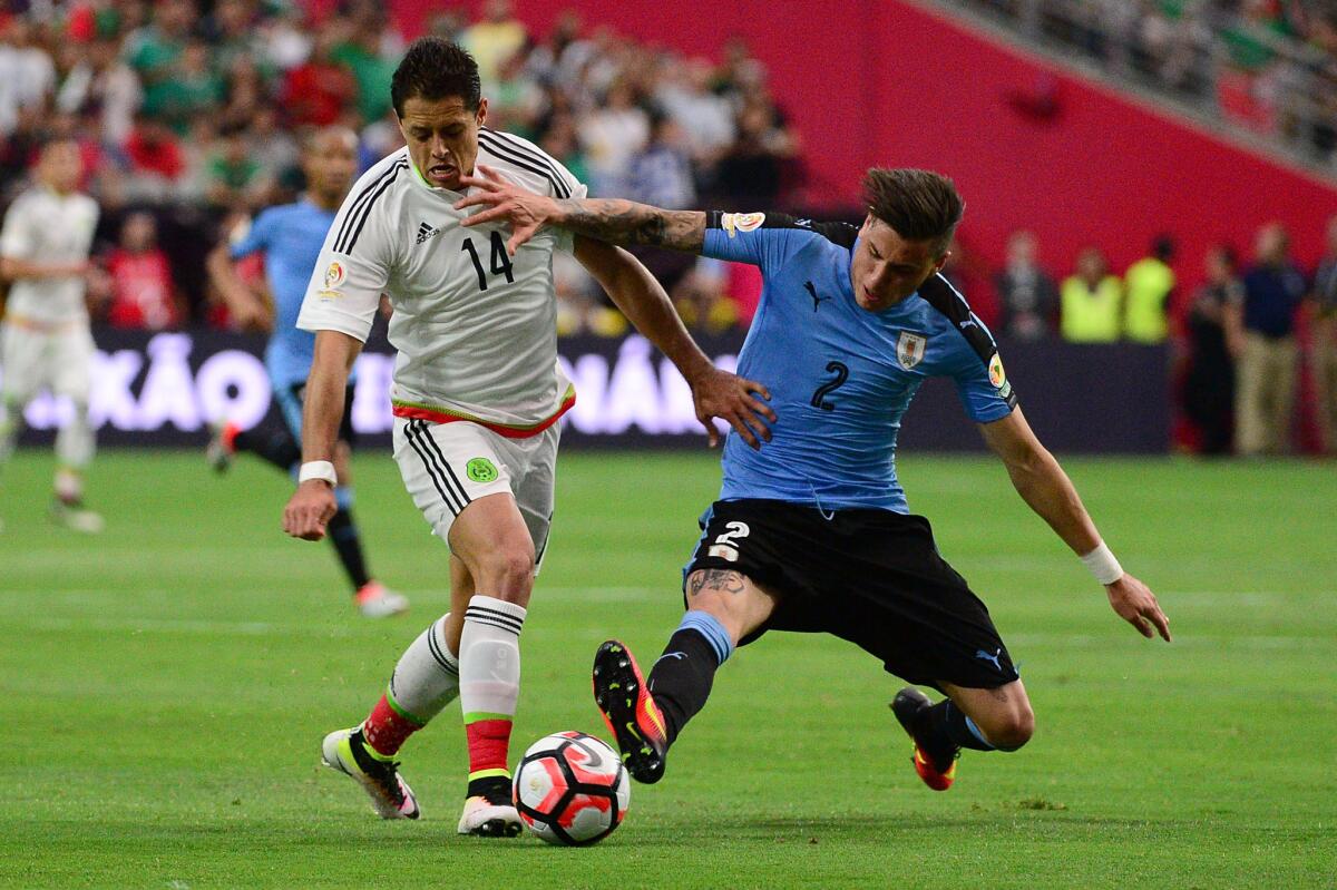 Uruguay's Jose Gimenez tries to stop Mexico's Javier Hernandez.