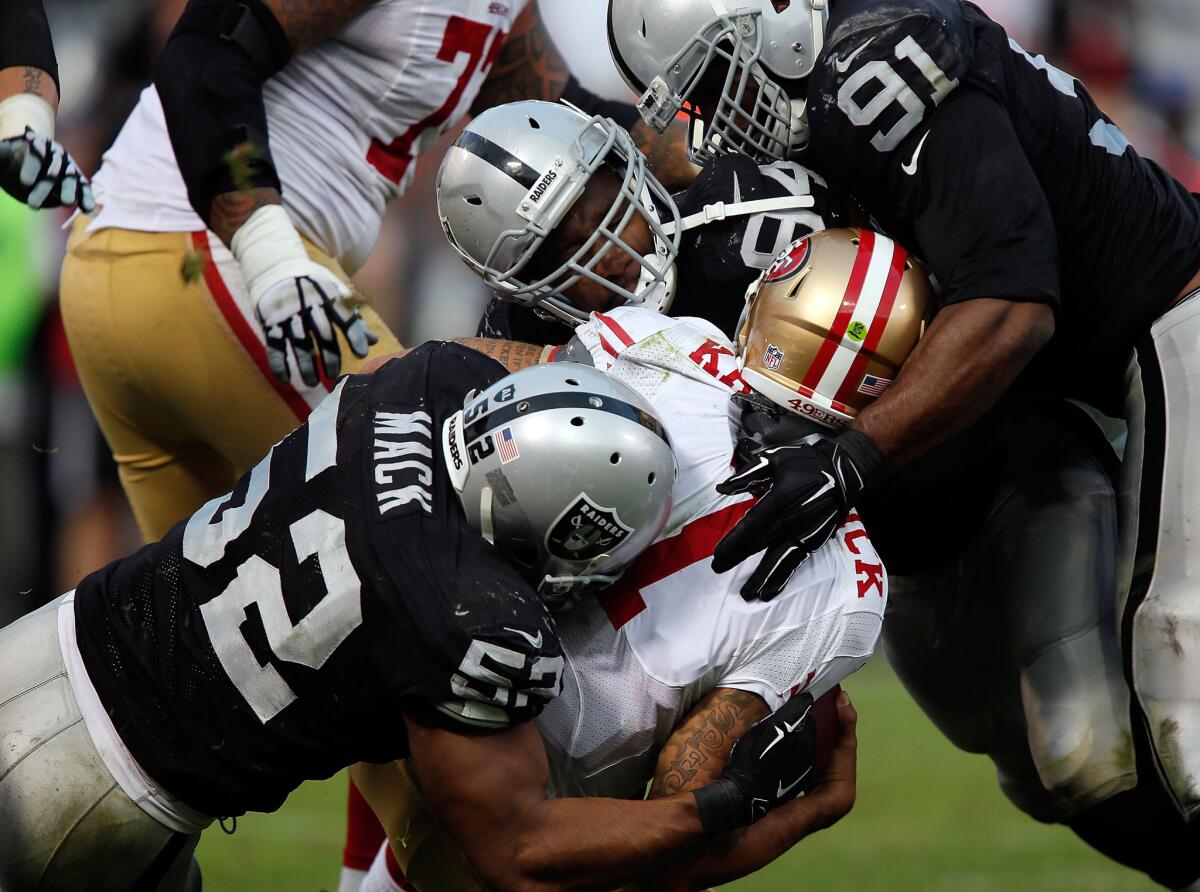 San Francisco 49ers quarterback Colin Kaepernick is sacked by Raiders defenders Khalil Mack, Antiono Smith and Justin Tuck during their game Sunday.