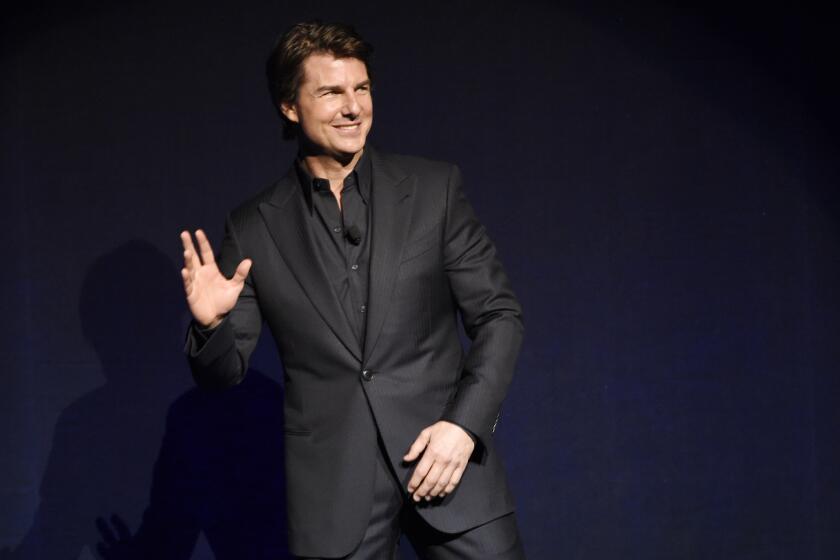 Tom Cruise, star of the upcoming film "Mission: Impossible -- Rogue Nation," waves to the audience during a surprise appearance at the Paramount Pictures presentation at CinemaCon.
