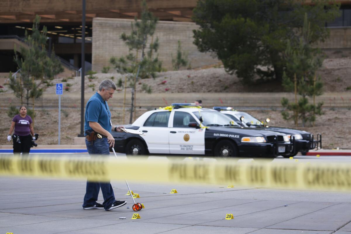 A member of the San Diego Police Department investigates and documents the scene. (Howard Lipin / San Diego Union-Tribune)