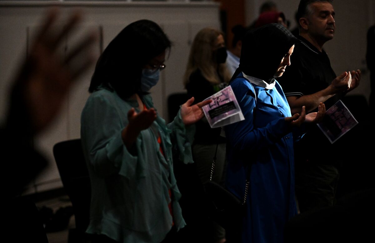 People hold booklets and pray.