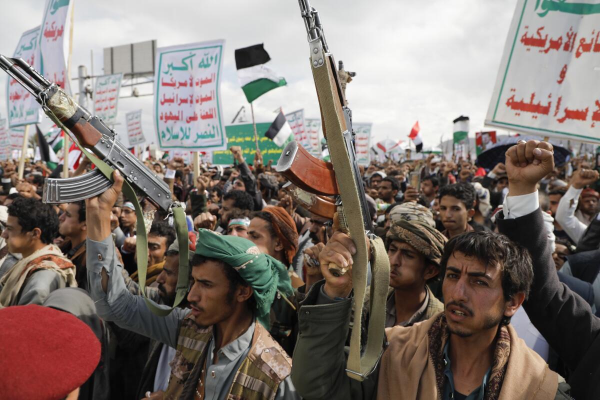 Houthi supporters hold guns and signs during a rally in Sana, Yemen.