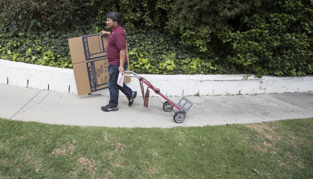 Balikbayan box shipper Norbyl Caburog heads off with empty boxes and a hand cart while picking up for customers shipping to family in the Philippines while on his route in Palos Verdes Estates, Calif. (Brian Van Der Brug / Los AngelesTimes)