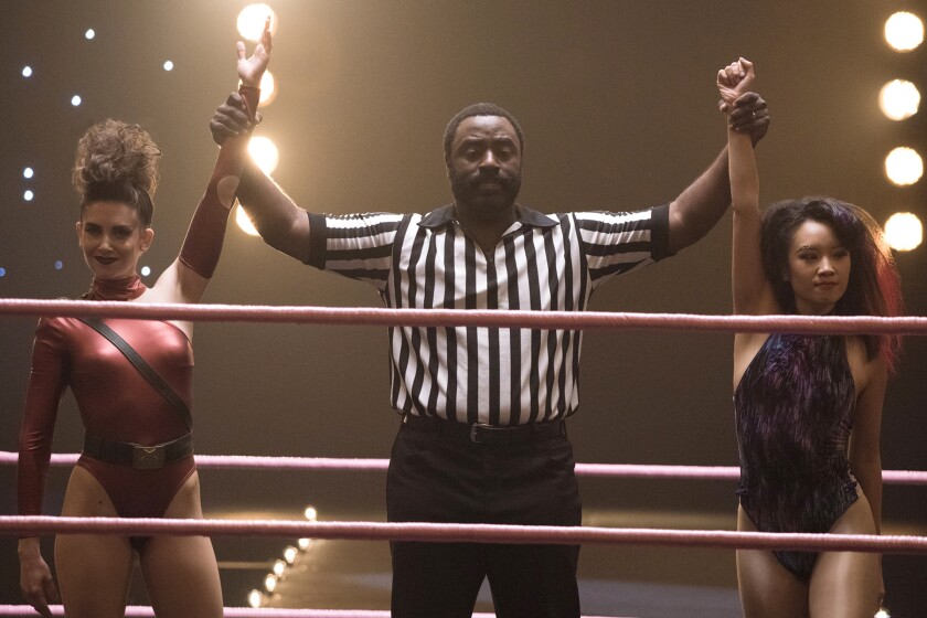 Two women wrestlers in the ring with a referee