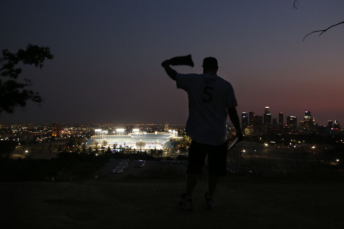 Dodgers fan Josh Gitt waves a bandanna while watching the Dodgers play the Milwaukee Brewers.
