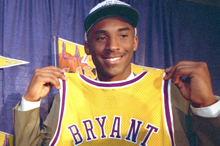 Lakers guard Kobe Bryant holds up his jersey during his introductory news conference on July 12, 1996.